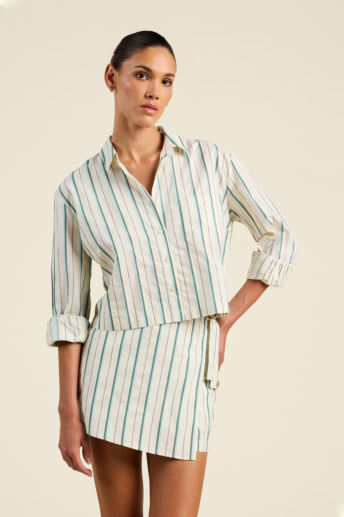 Woman wearing a striped dress with rolled-up sleeves on a beige background