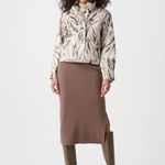 Woman wearing a patterned jacket, brown skirt, and brown boots on a white background