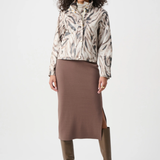 Woman wearing a patterned jacket, brown skirt, and brown boots on a white background