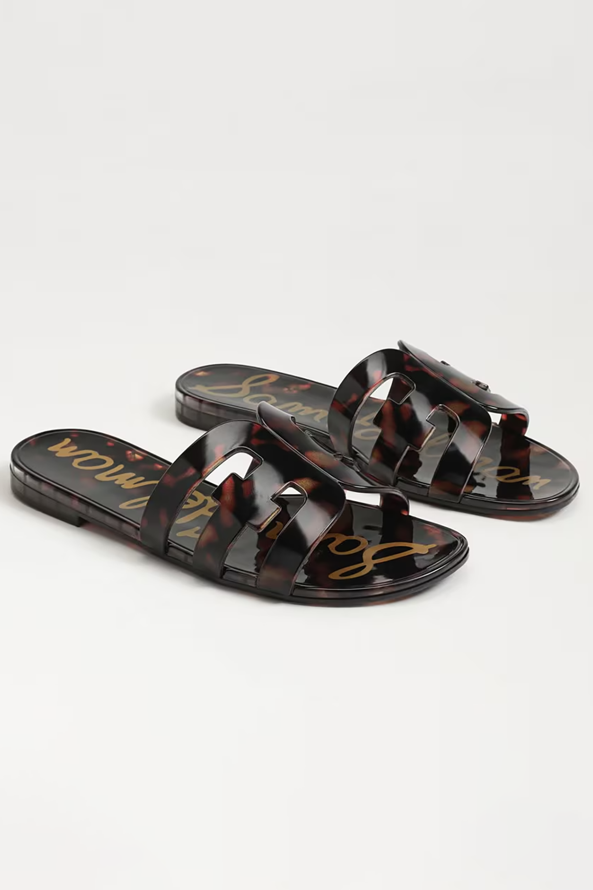 Pair of tortoiseshell sandals with gold text on a light gray background