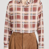 Person wearing a plaid shirt and brown shorts on a white background