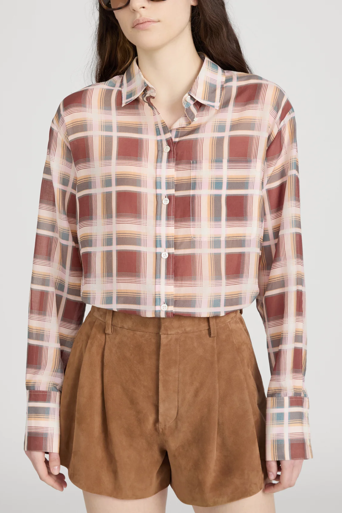 Person wearing a plaid shirt and brown shorts on a white background