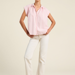 Woman wearing a pink striped shirt and white pants on a beige background