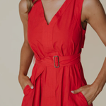 Red dress with a belt worn by a person on a beige background
