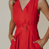 Red dress with a belt worn by a person on a beige background