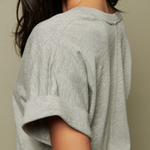 Close-up of a person wearing a light gray textured top against a neutral background