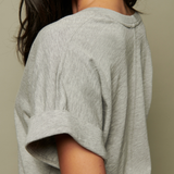 Close-up of a person wearing a light gray textured top against a neutral background