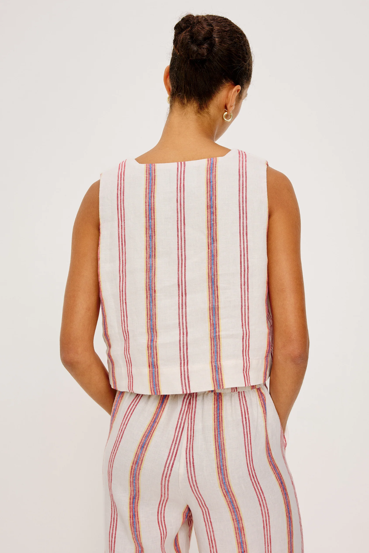 Person wearing a sleeveless striped top and pants on a white background