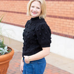 Knit sweater with puff sleeves and pom pom texture, styled with denim.