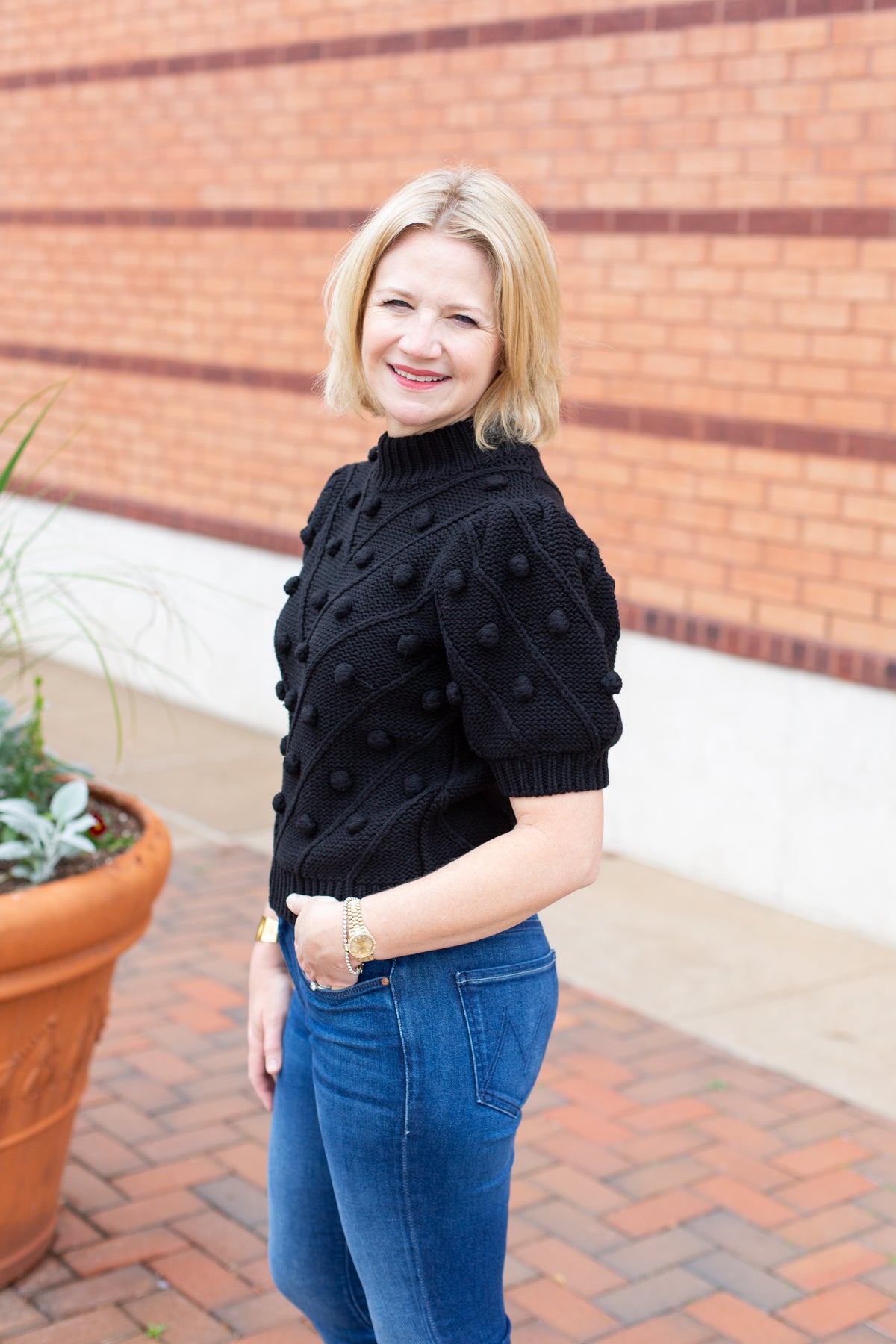 Knit sweater with puff sleeves and pom pom texture, styled with denim.
