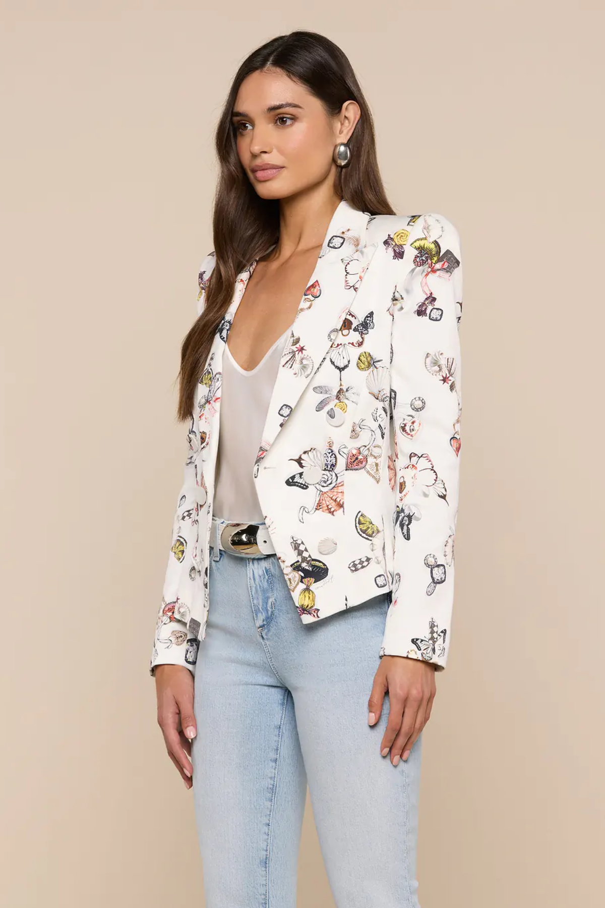 Woman wearing a white blazer with colorful butterfly pattern on a beige background