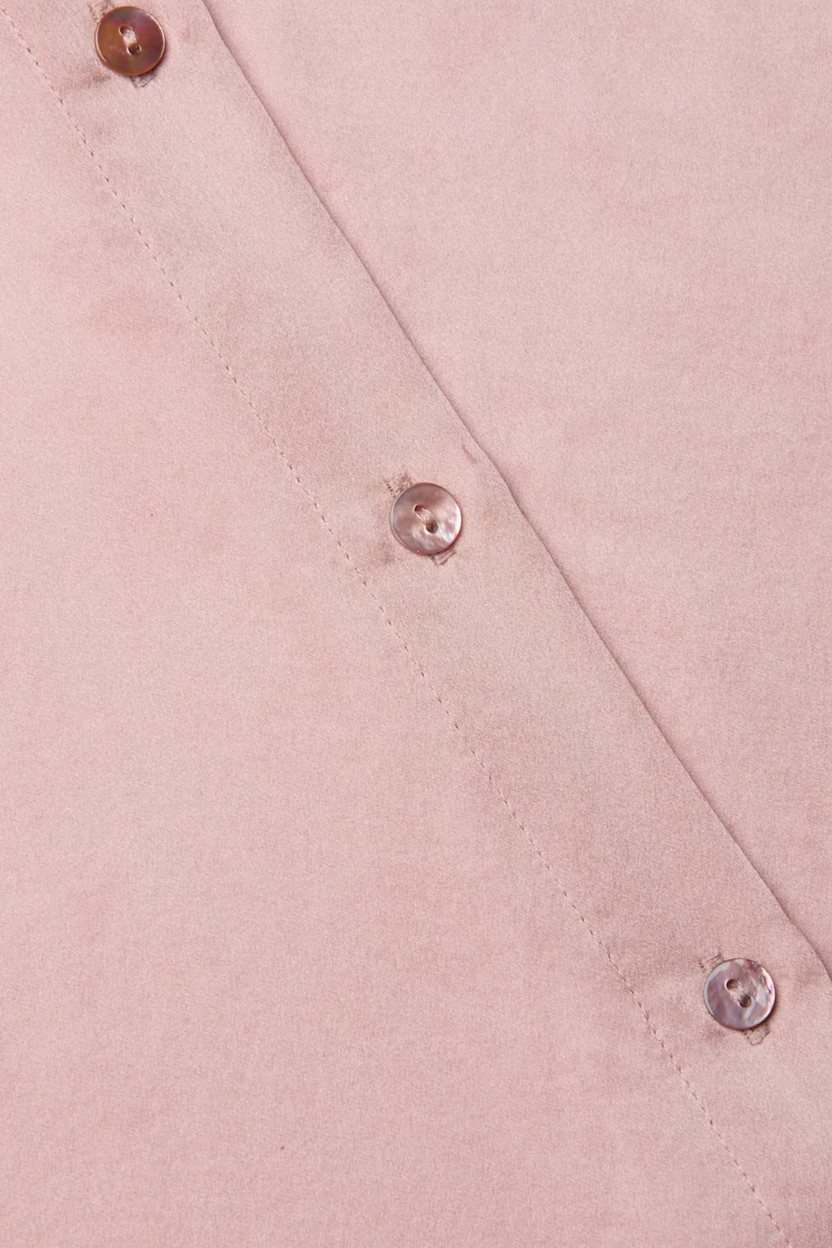 Close-up of a pink fabric with buttons on a matching pink background