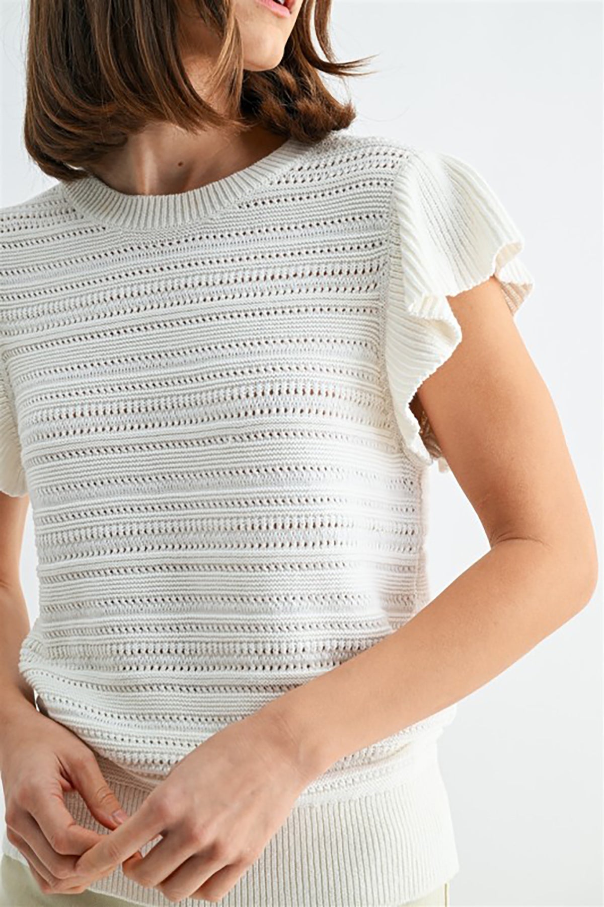 White textured top worn by a person on a white background