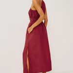 Woman wearing a burgundy strapless dress with a slit on a white background