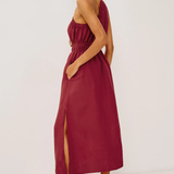 Woman wearing a burgundy strapless dress with a slit on a white background