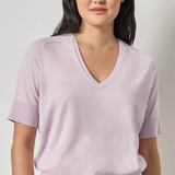 Woman wearing a light purple V-neck sweater against a plain background