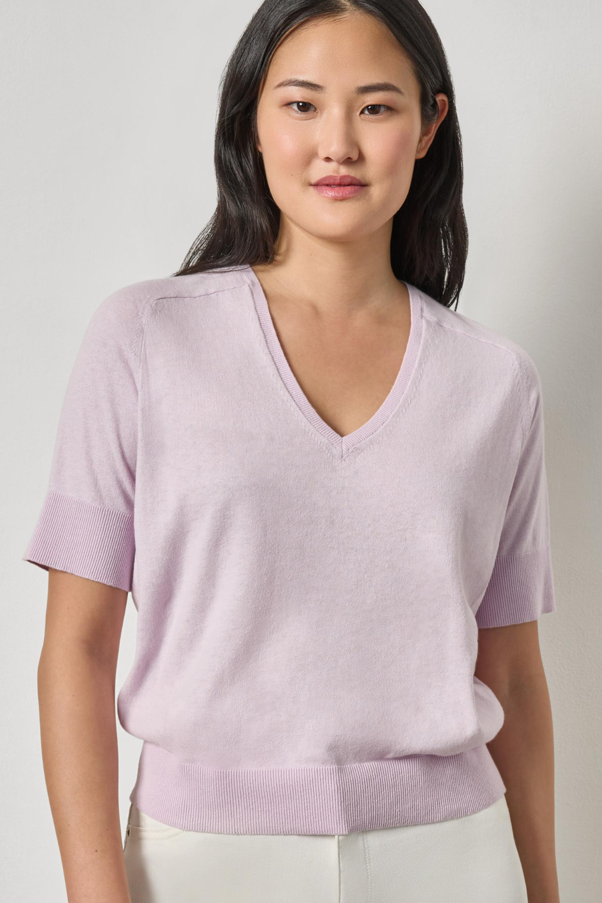 Woman wearing a light purple V-neck sweater against a plain background