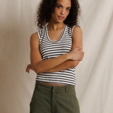 Woman wearing a striped tank top and green pants against a neutral background