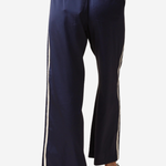A person wearing navy wide-leg pants with white side stripes, shown from the back against a light gray studio background.