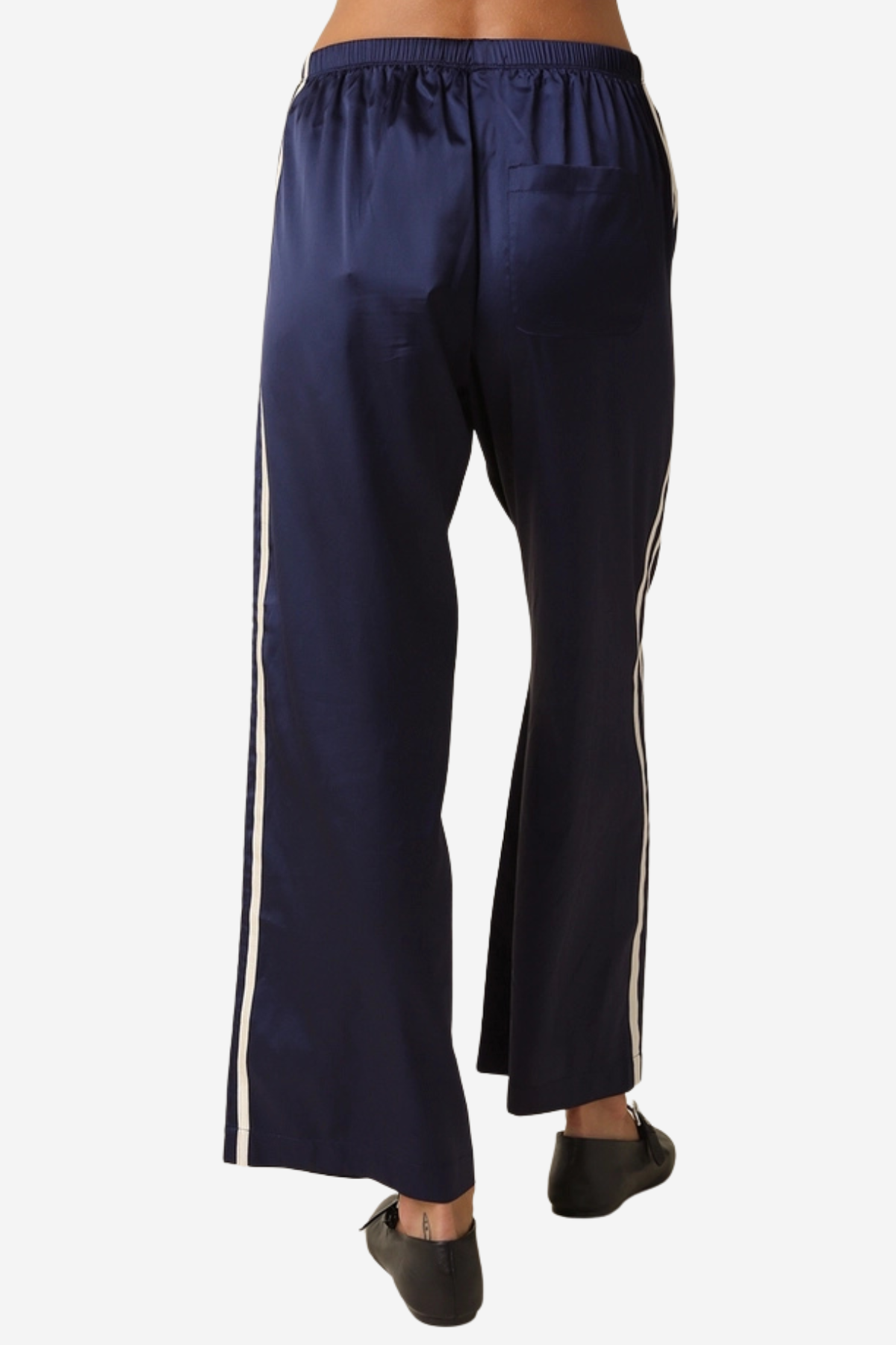A person wearing navy wide-leg pants with white side stripes, shown from the back against a light gray studio background.