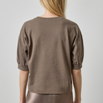 Woman wearing a brown top and skirt against a plain background