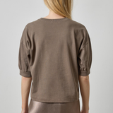 Woman wearing a brown top and skirt against a plain background