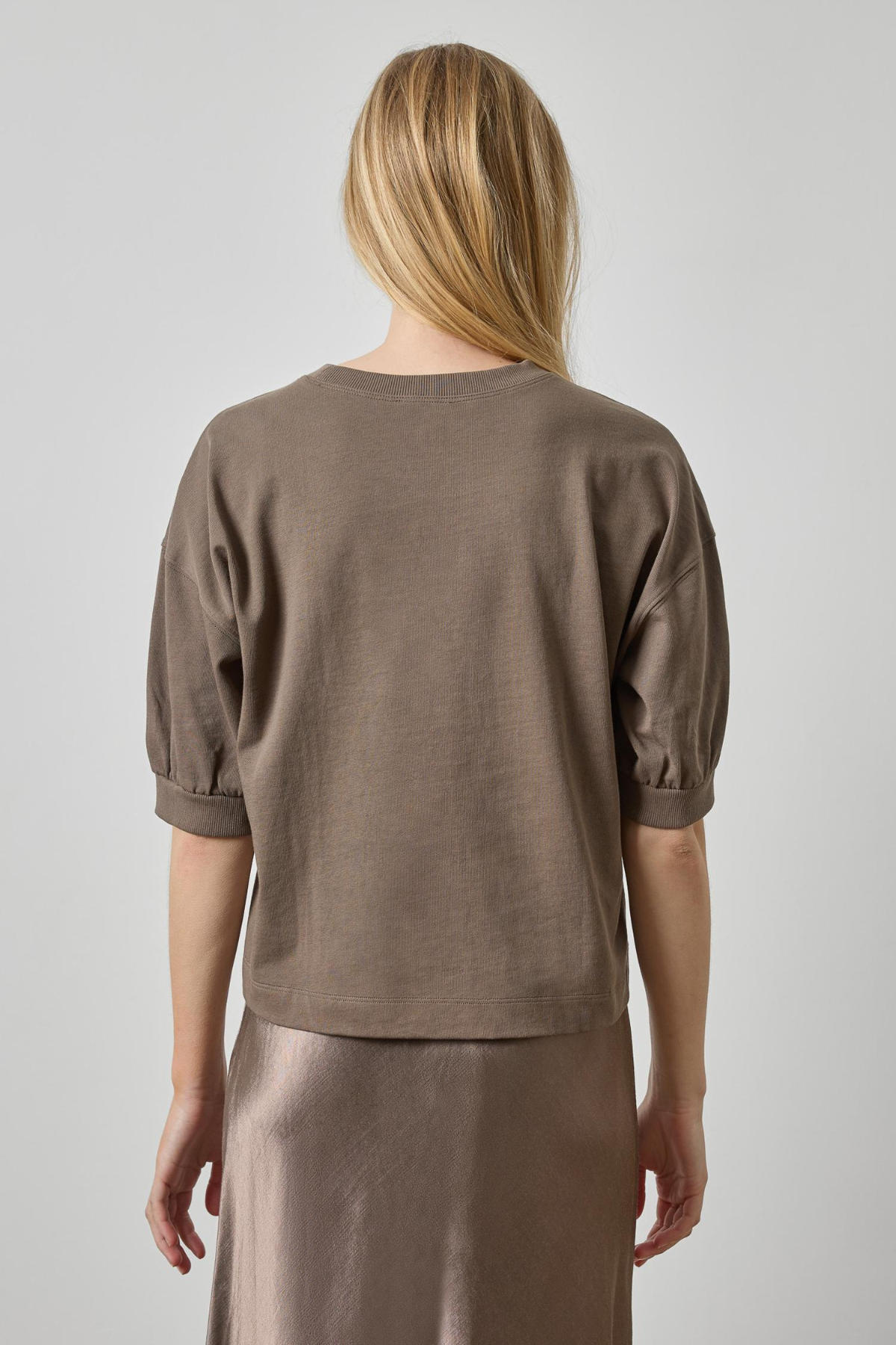 Woman wearing a brown top and skirt against a plain background
