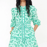 woman in printed green mini dress on white background 