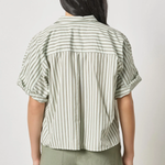 Person wearing a striped shirt and green shorts on a plain background