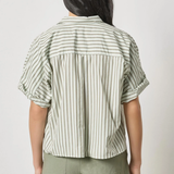 Person wearing a striped shirt and green shorts on a plain background