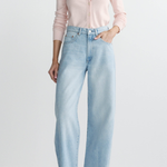 Person wearing light blue jeans and a pink shirt on a white background