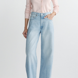 Person wearing light blue jeans and a pink shirt on a white background