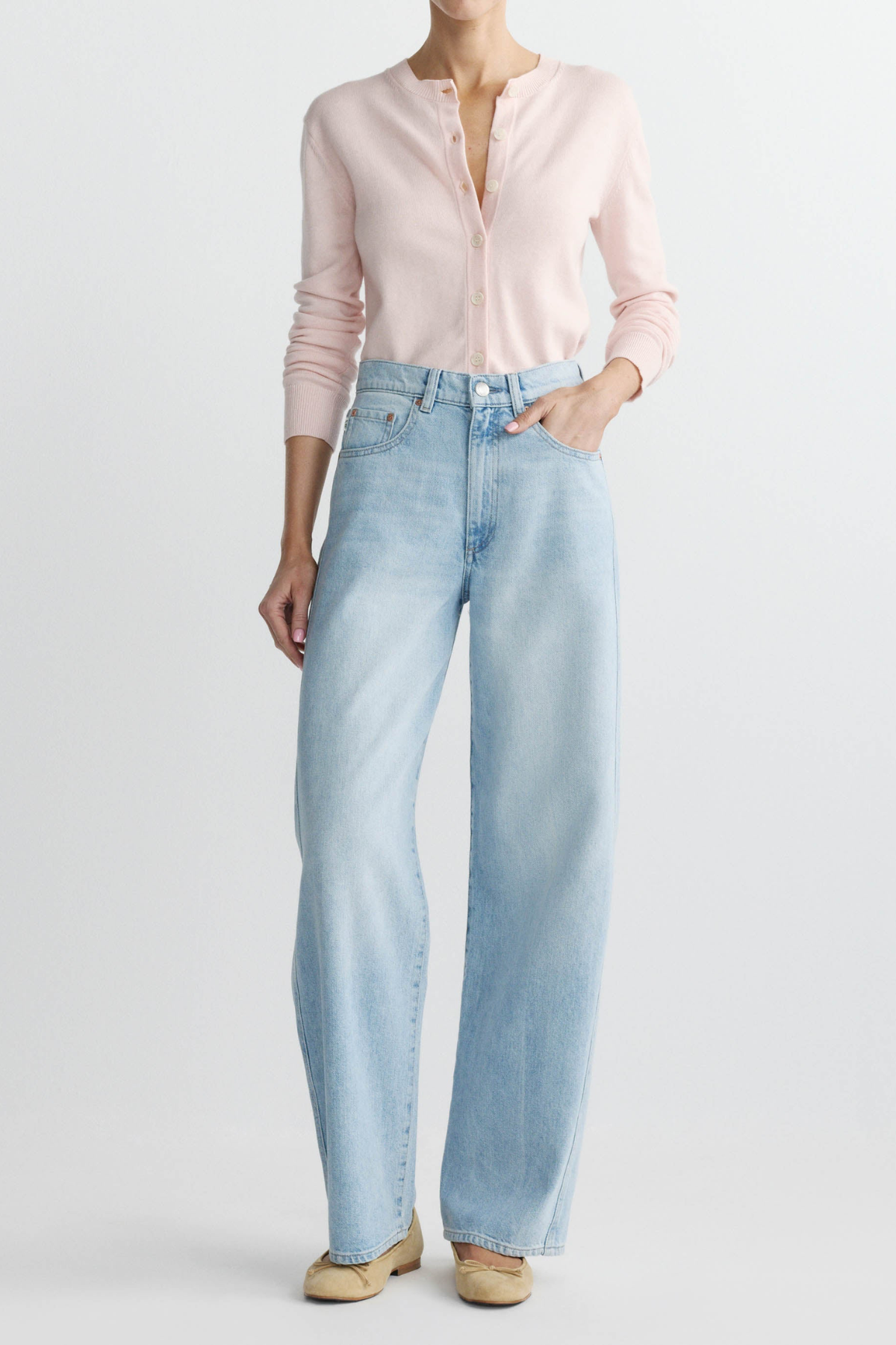 Person wearing light blue jeans and a pink shirt on a white background