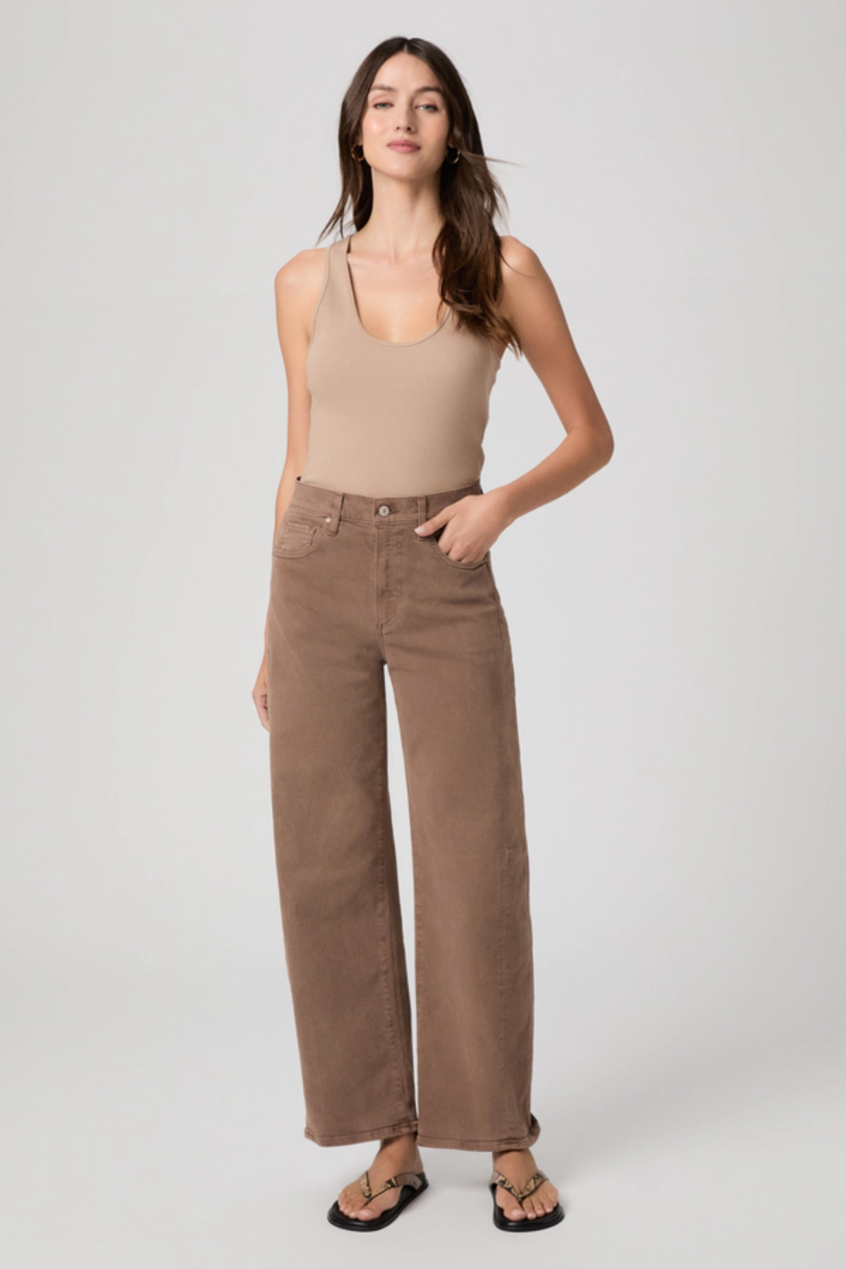 Woman wearing a beige tank top and wide-leg pants on a white background