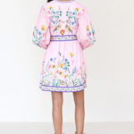 Woman wearing a pink dress with floral embroidery on a white background