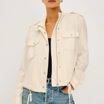 Woman wearing a cream jacket and blue jeans on a white background