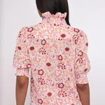 pink printed short sleeve blouse with ruffles on model against a white background