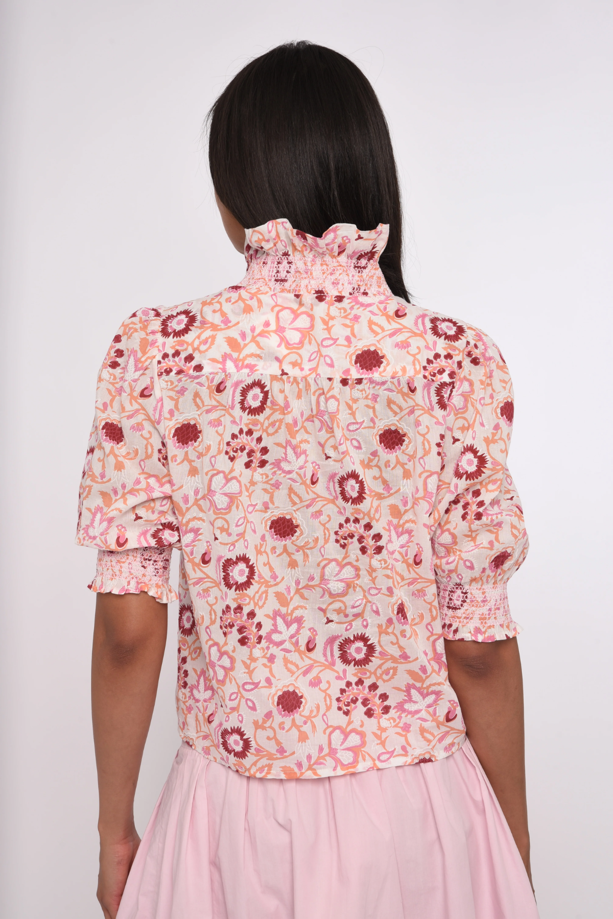 pink printed short sleeve blouse with ruffles on model against a white background