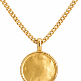 A gold-toned necklace featuring a textured, circular disc pendant suspended from a matching curb chain, set against a plain white background.