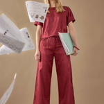 Woman in red outfit holding papers against a beige background