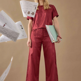 Woman in red outfit holding papers against a beige background