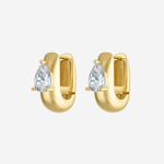 A pair of gold huggie hoop earrings, each featuring a pear-cut clear gemstone in a prong setting, shown against a light gray background.