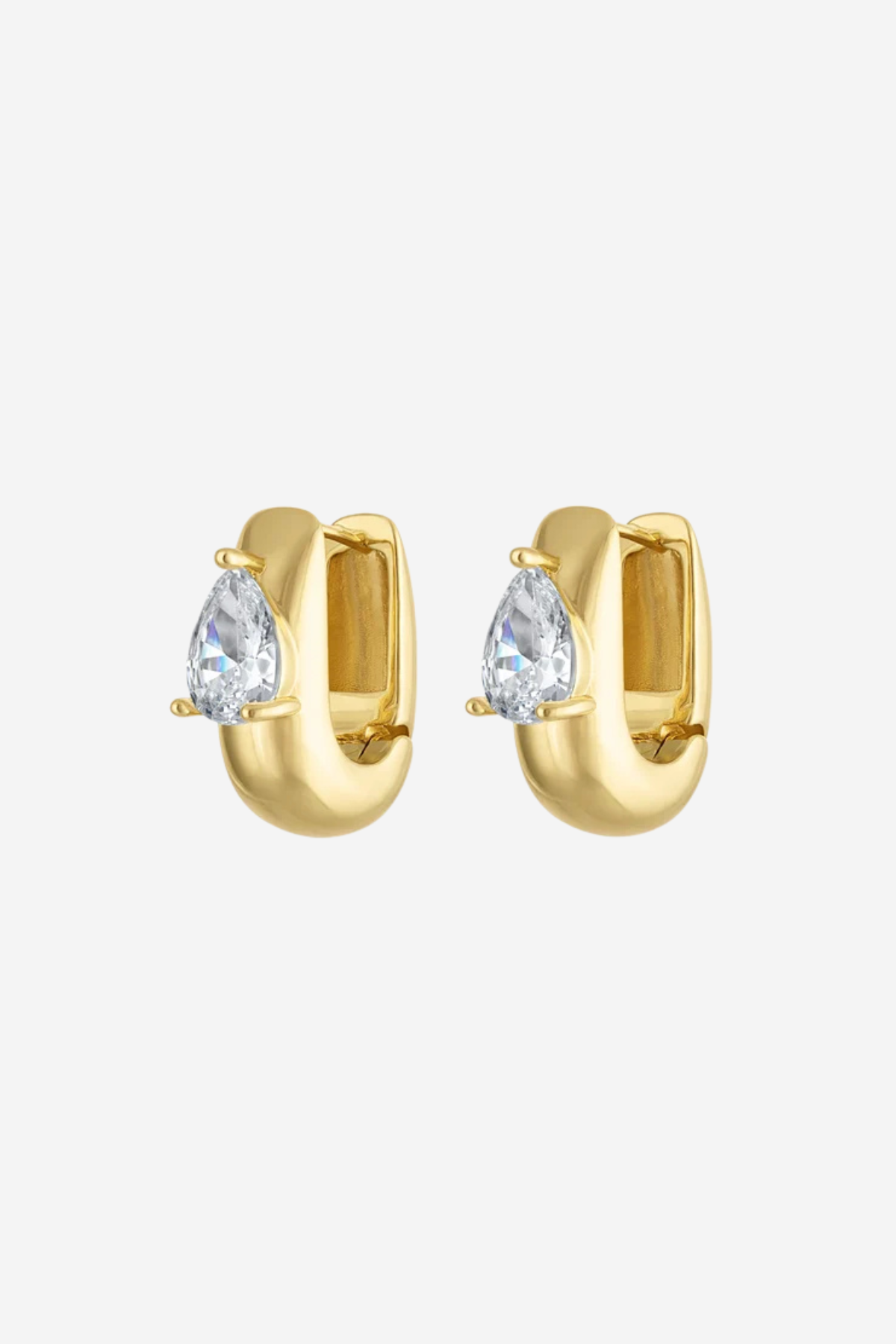 A pair of gold huggie hoop earrings, each featuring a pear-cut clear gemstone in a prong setting, shown against a light gray background.