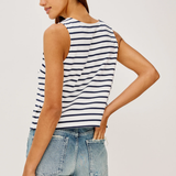 Woman wearing a striped tank top and jeans on a plain background