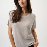 Woman wearing a beige short-sleeve top against a white background