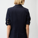 Person wearing a navy blazer with rolled-up sleeves on a plain background