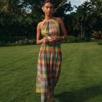 Woman in a colorful dress standing on grass with trees in the background
