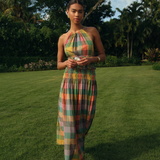 Woman in a colorful dress standing on grass with trees in the background