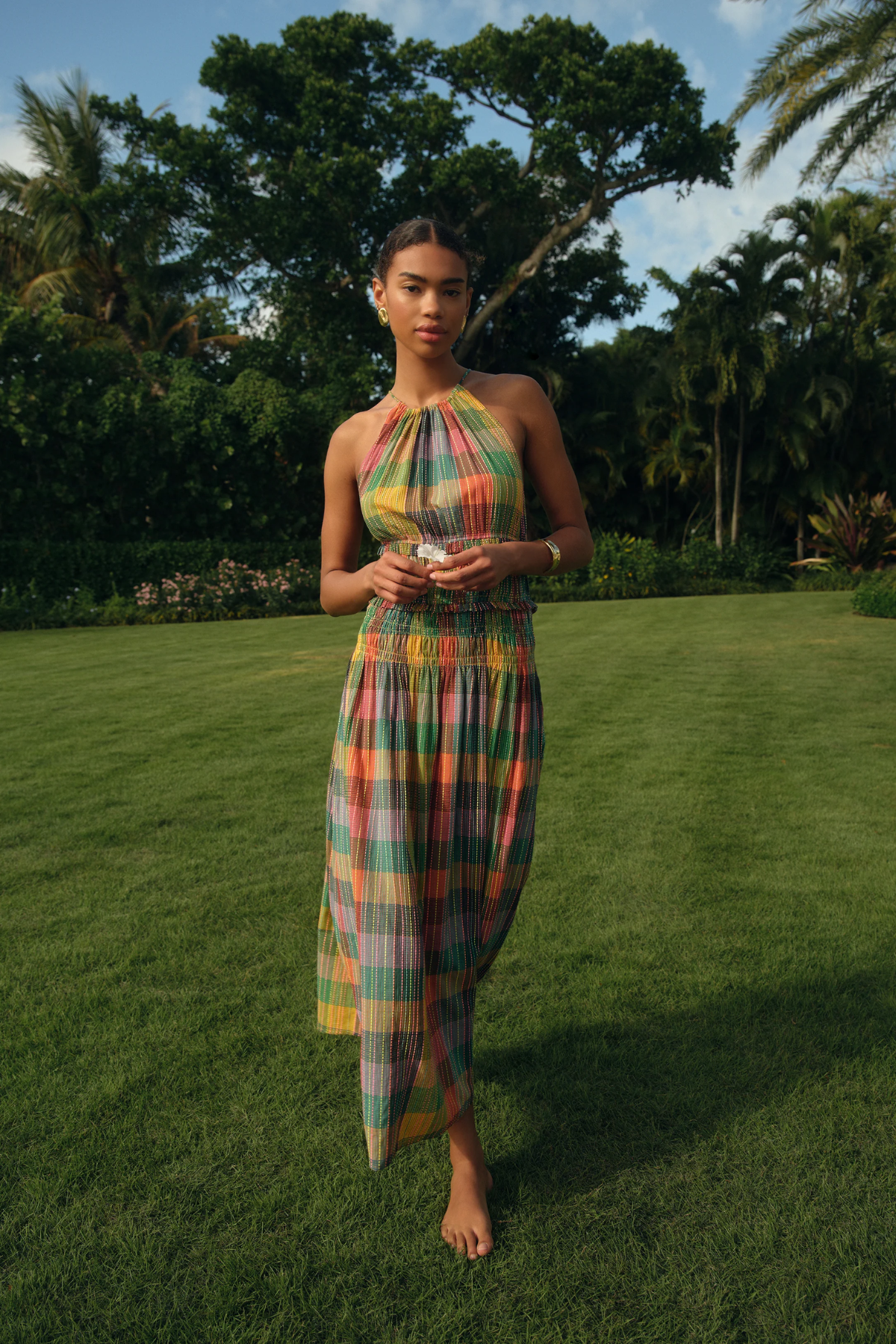 Woman in a colorful dress standing on grass with trees in the background