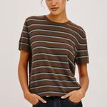 Woman wearing a brown and blue striped t-shirt against a plain background